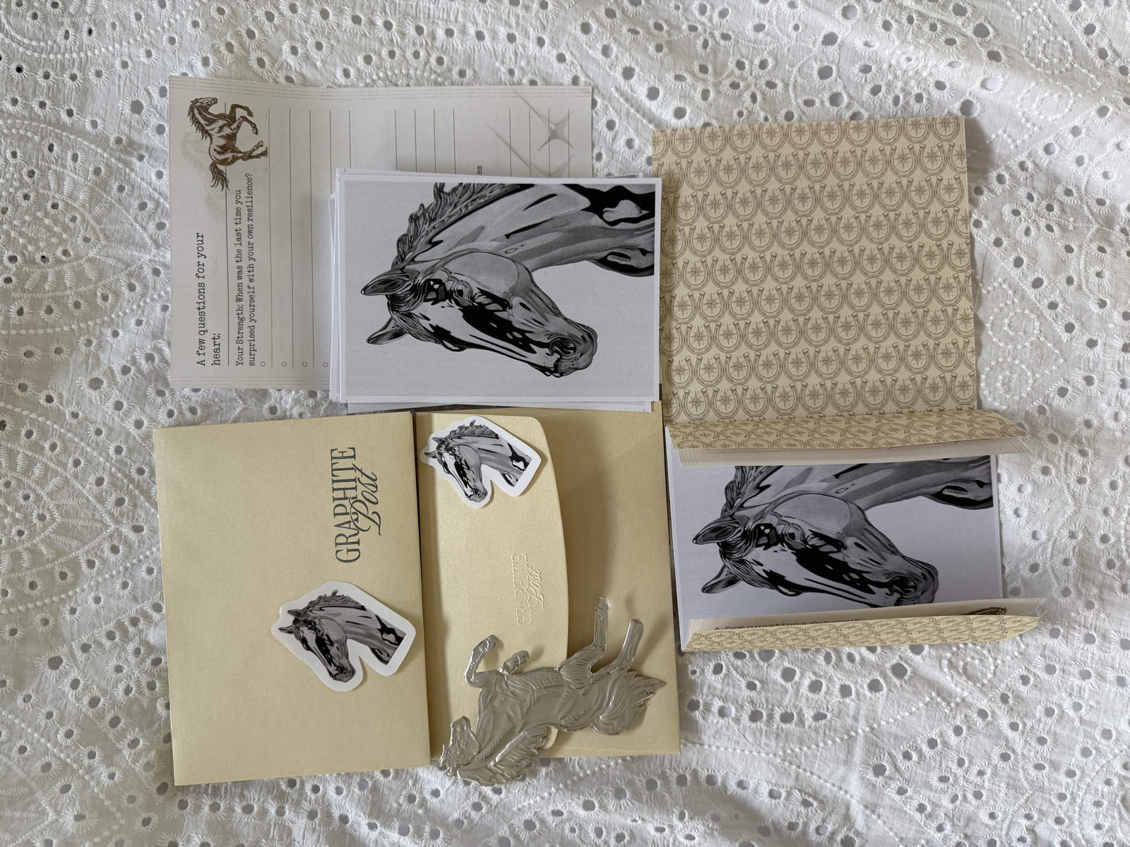 Graphite Post horse collection — package contents on white linen with prints, stickers and envelope