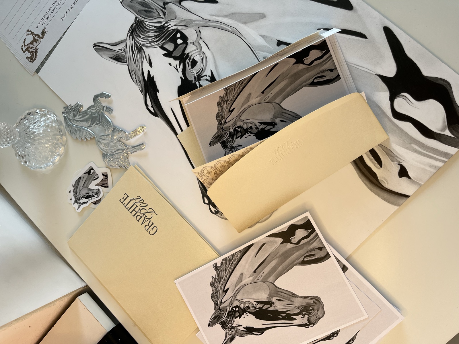 Horse art prints and package contents on studio desk overhead view