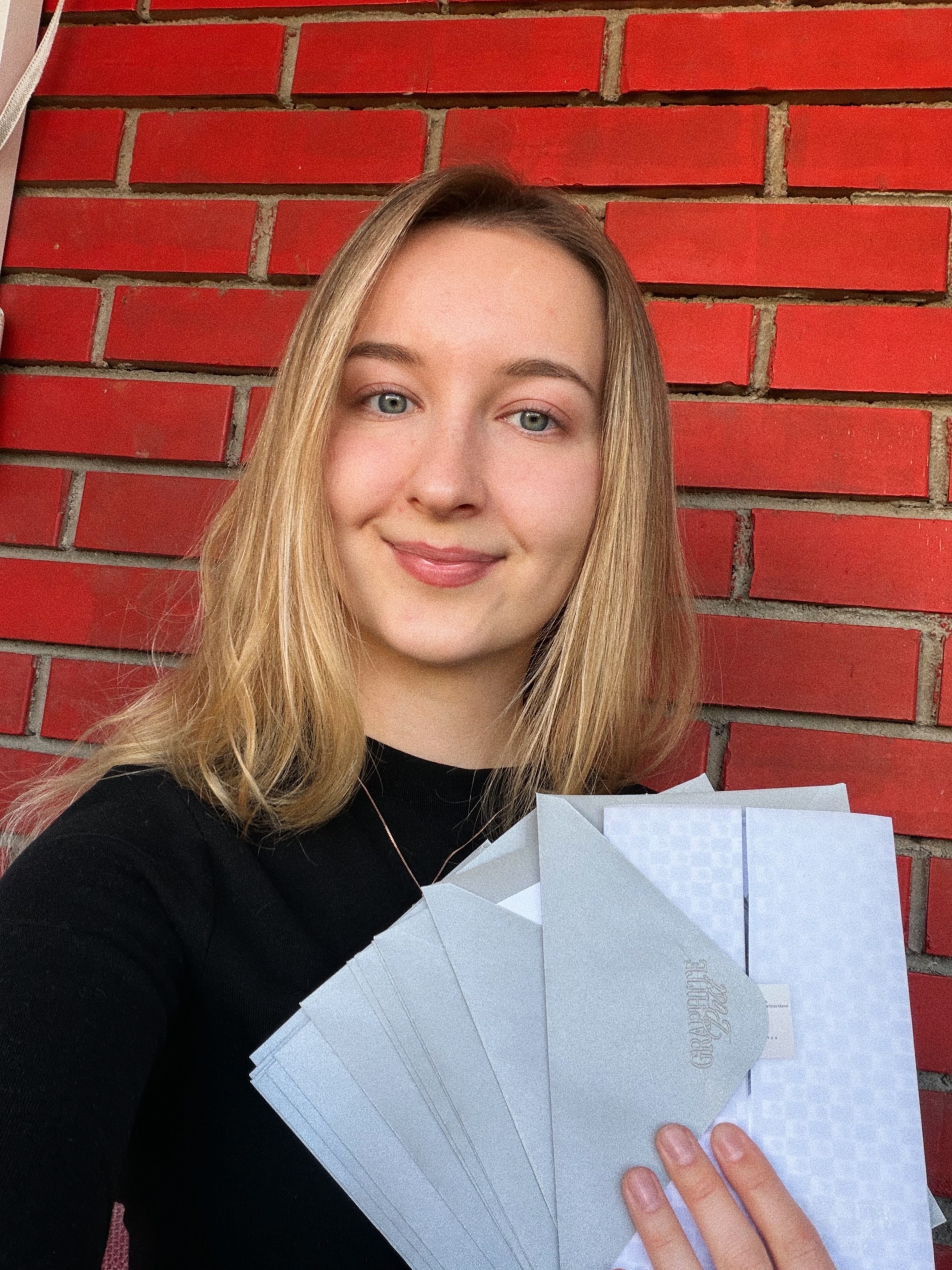 Julia, the artist behind Graphite Post, holding envelopes