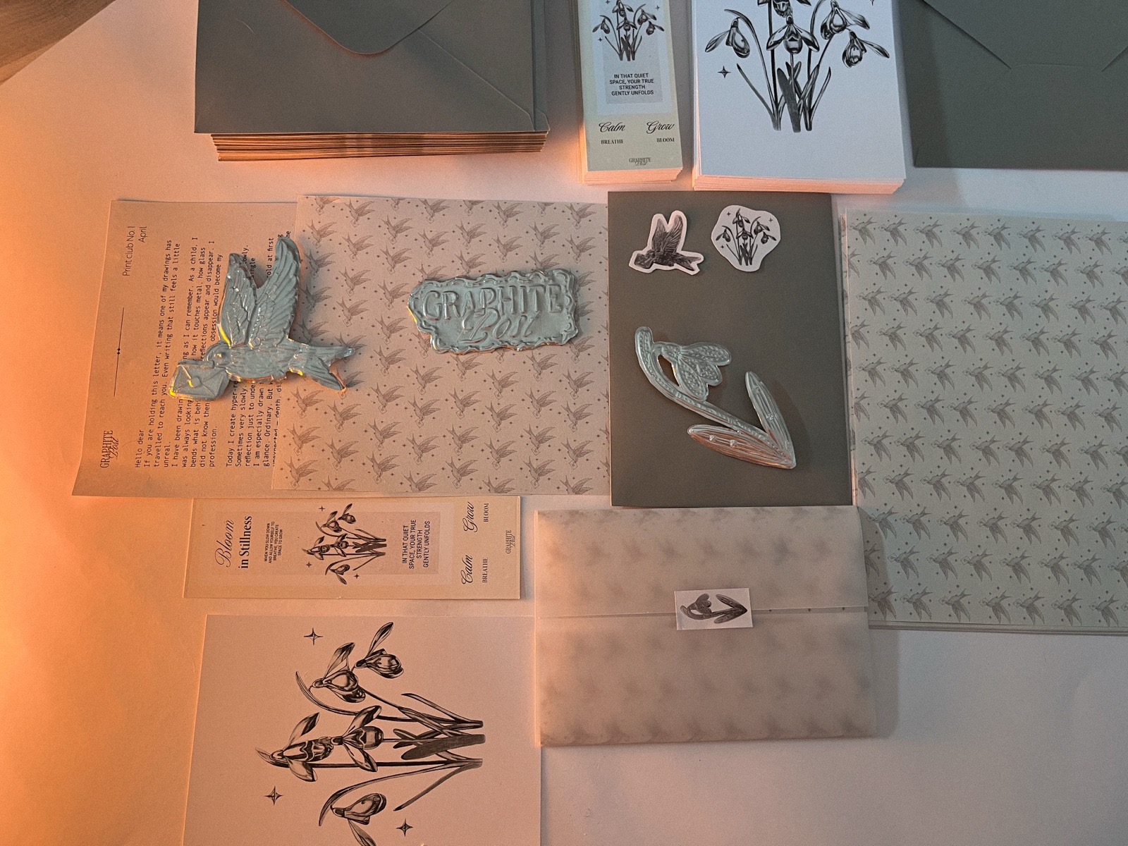 Complete Graphite Post package flatlay with print, stickers, bookmark, and letter