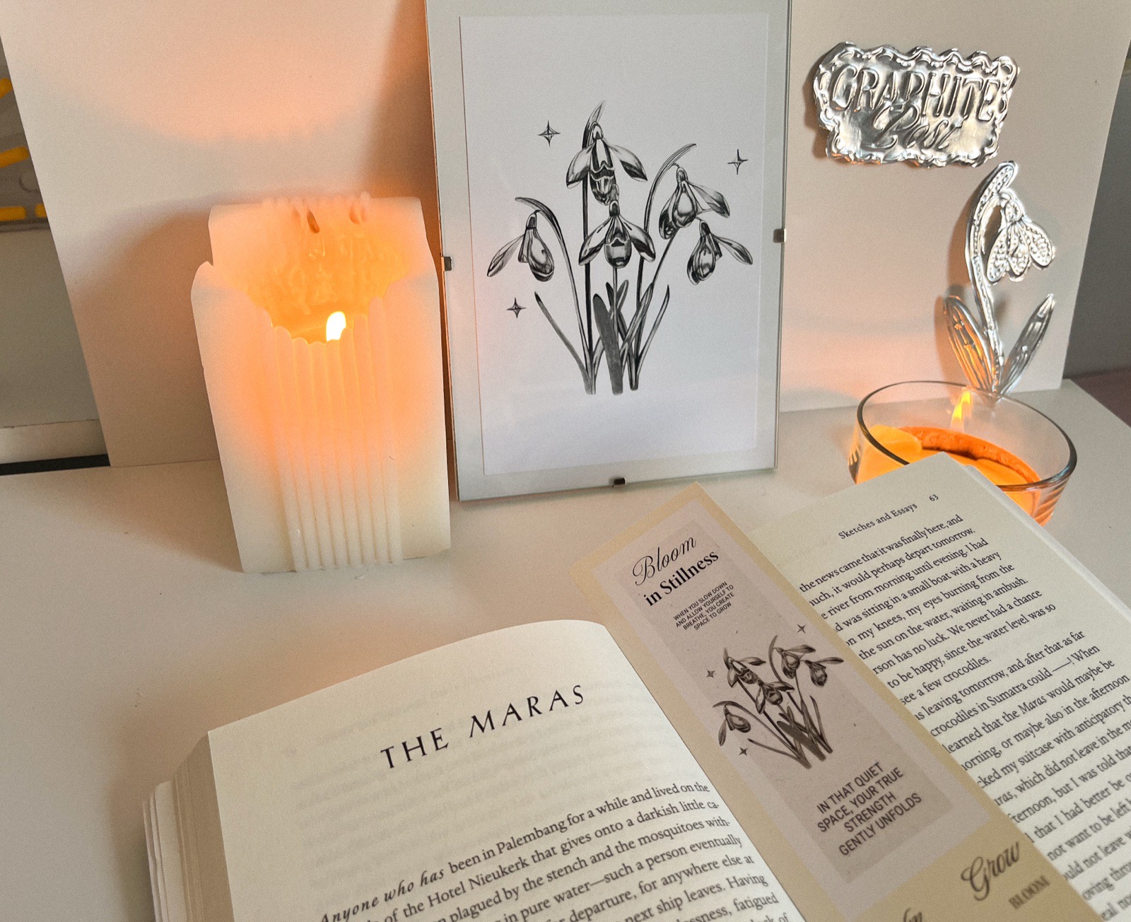 Snowdrop pencil art print displayed with book and candle